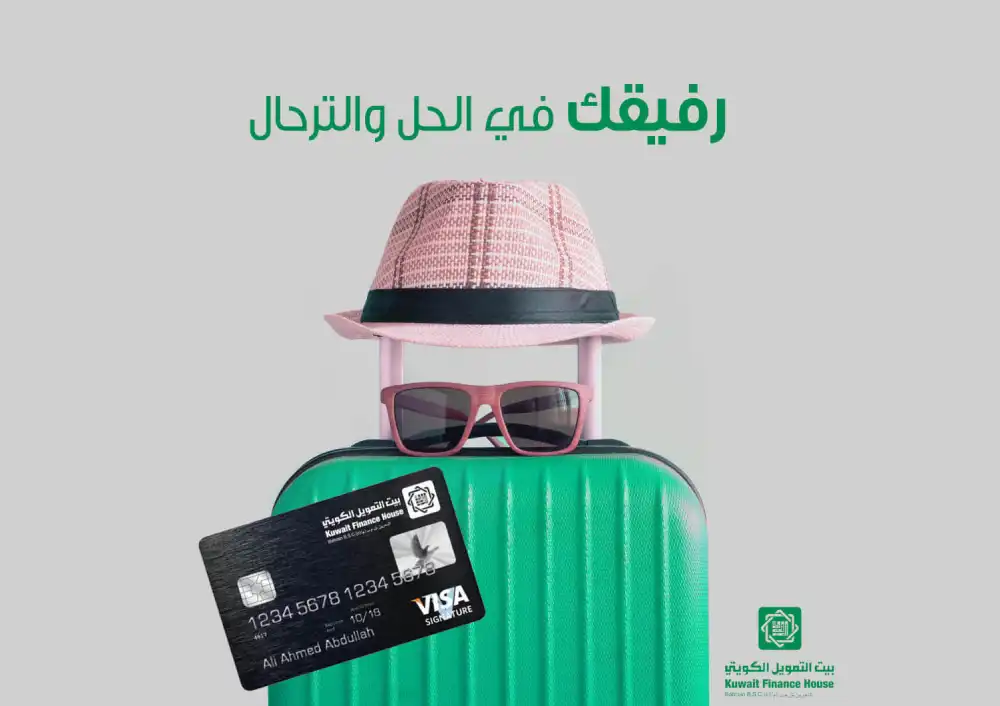  Kuwait Finance House Visa Signature card placed in front of a green suitcase with a hat and sunglasses on top