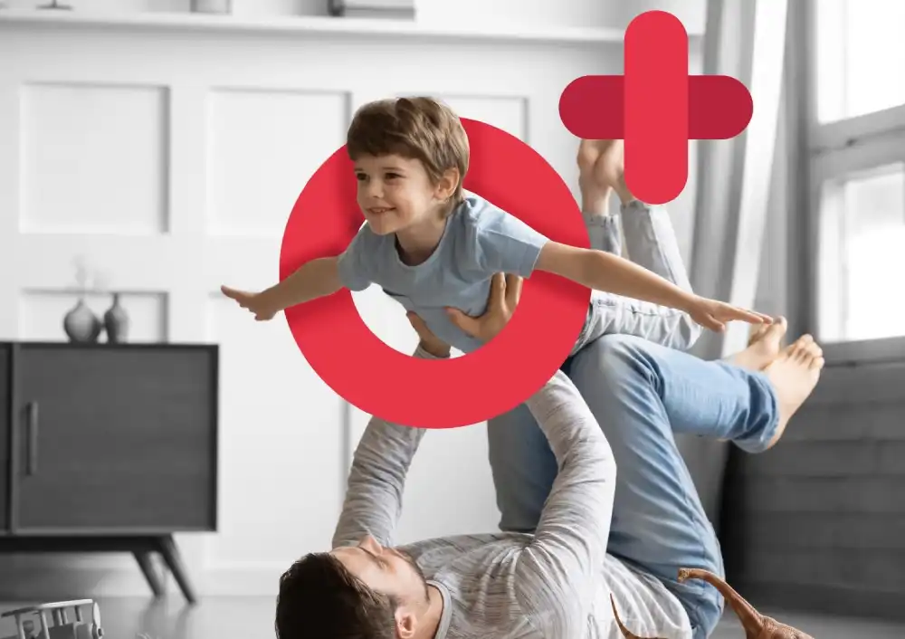 A joyful scene of a father playing with his son, who is being lifted into the air, with a prominent red circular logo and a plus sign overlay, representing O PLUS Pharmacy.