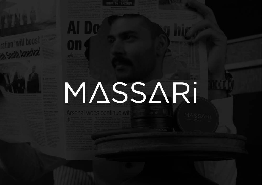 A stylish man reading a newspaper with a close-up of MASSARI grooming products displayed on a wooden surface, featuring the brand logo prominently.